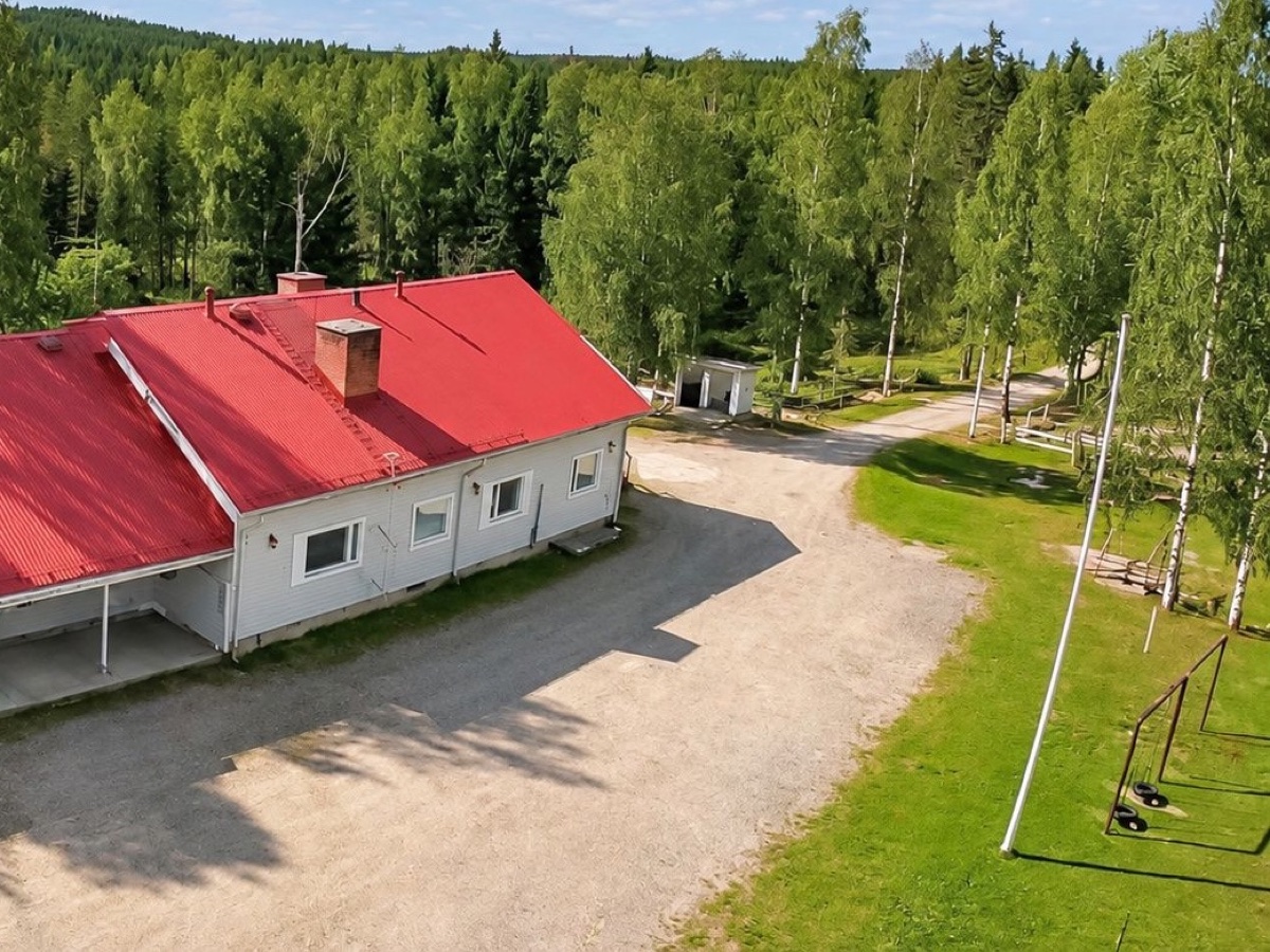 Lumiar Solinan valkoinen, punakattoinen talo, piha ja koivut metsän keskellä kesällä ilmasta kuvattuna